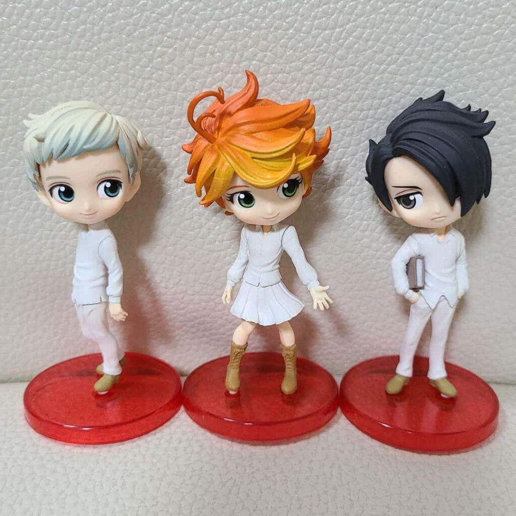 Toy figures of Emma Ray and Norman from The Promised Neverland on red bases wallpaper background