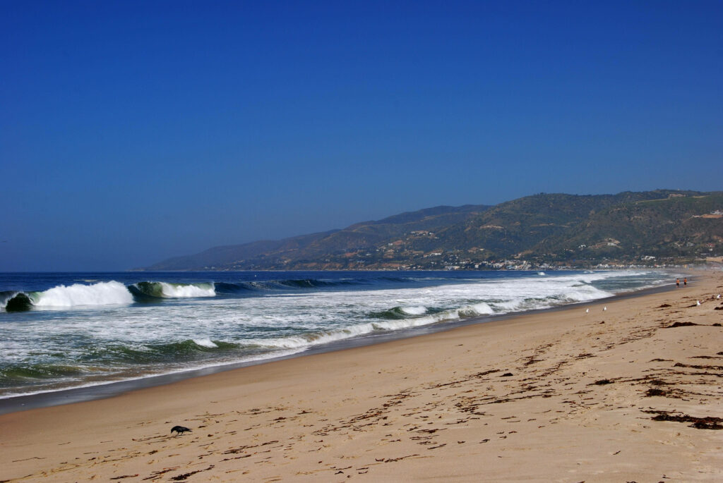 Malibu Bliss: Basking in Clear Weather on the Brown Shores of the Wavy Sea Wallpaper