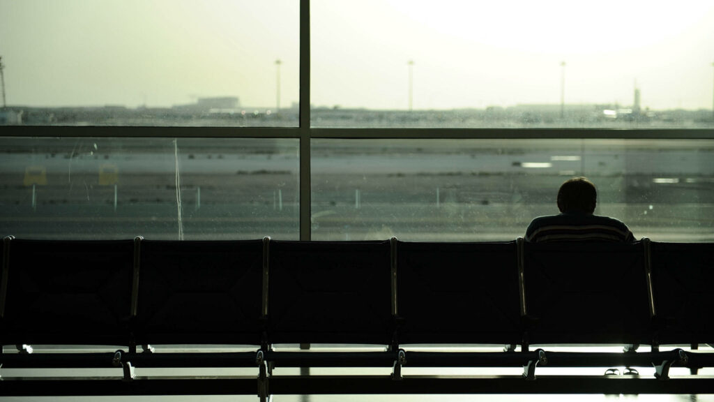 Solitude in an Airport Oasis: An Empty Chair Amidst the Overcast Airport Scenery Wallpaper