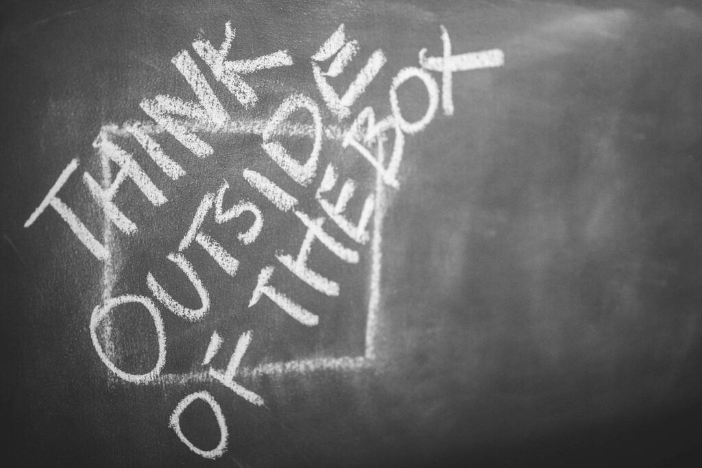 Chalkboard wallpaper with think outside the box motivational phrase in bold white chalk text