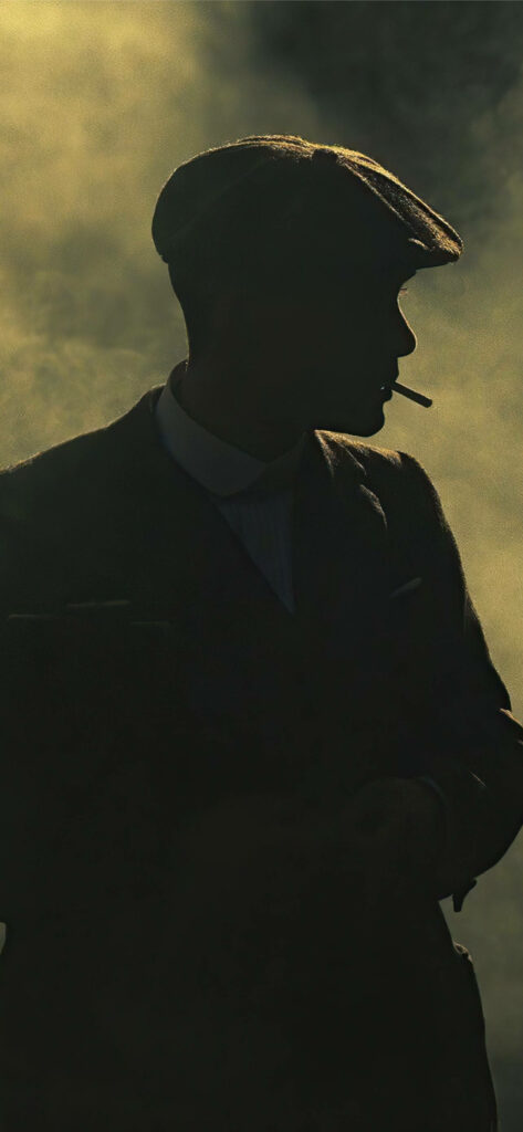 Enigmatic Icon: Thomas Shelby from Peaky Blinders Roams Through Shadows with a Stylish Phone Background Wallpaper
