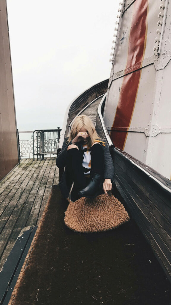 Amy Nelson sitting thoughtfully by slide with rustic wood and metal railings moody candid scene Wallpaper