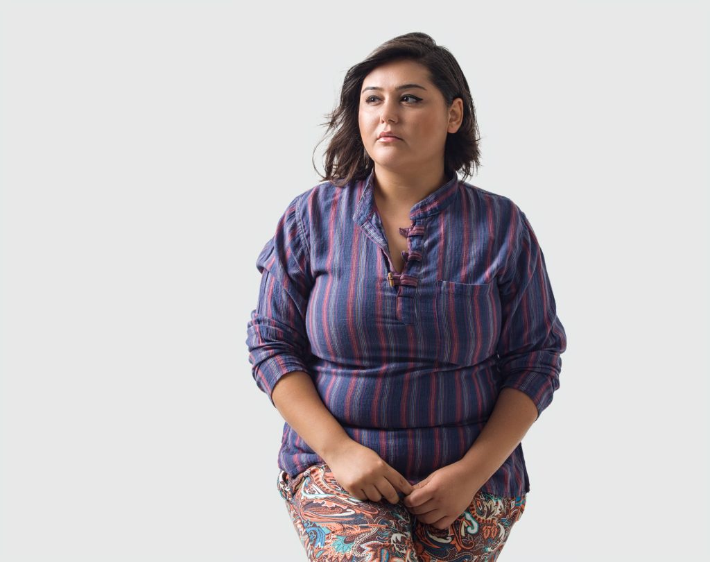 Pensive plus-size woman in striped shirt and paisley pants studio portrait with soft lighting Wallpaper