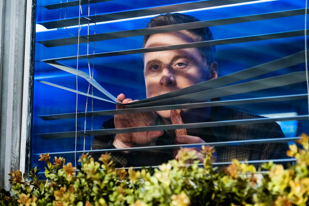 Thoughtful Character Peering Through Blinds - Resident Alien Wallpaper