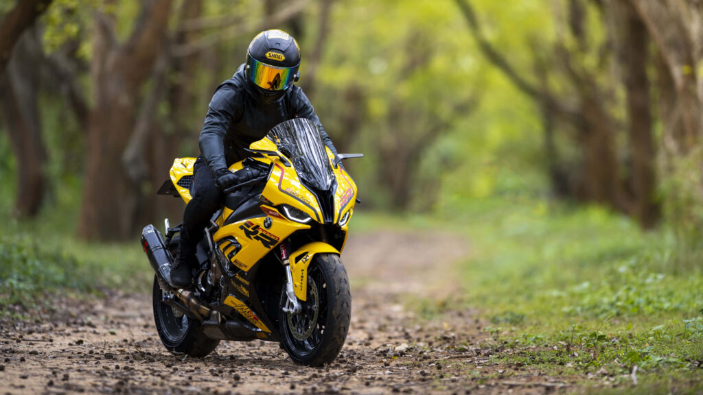 Thrilling Yellow Motorcycle Adventure Wallpaper in Lush Green Nature