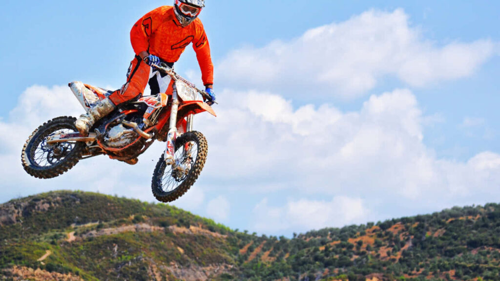 Thrilling 720p Motocross Wallpaper: Rider in Orange Gear Mid-Air