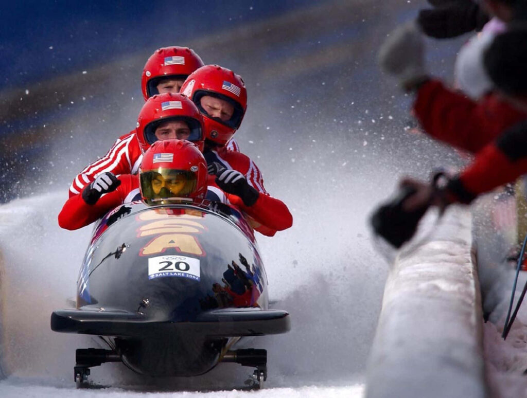 Thrilling Bobsledding Action: Focused Team Racing on Icy Track Wallpaper