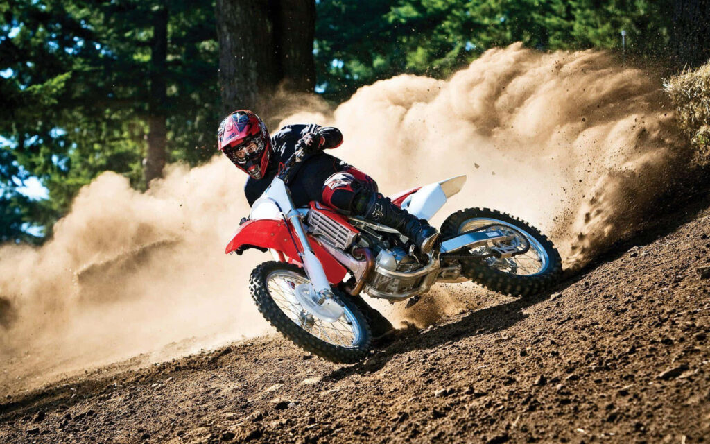 Thrilling Dirt Bike Rider Wallpaper: Rugged Trail Adventure Background