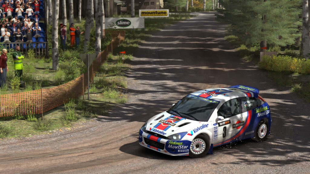 Rally car racing on gravel corner kicking up dust with cheering fans on forest rally track wallpaper