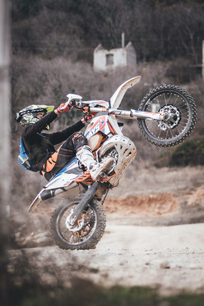 Thrilling Dirtbike Rider Wheelie Wallpaper - Adventure on Rugged Terrain