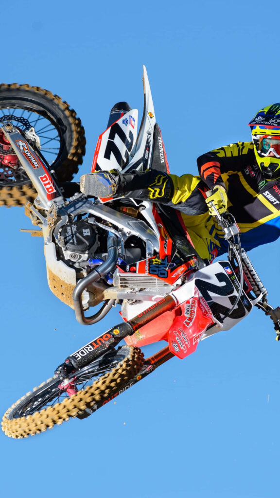 Thrilling Honda Dirt Bike Stunt Wallpaper Against Clear Blue Sky