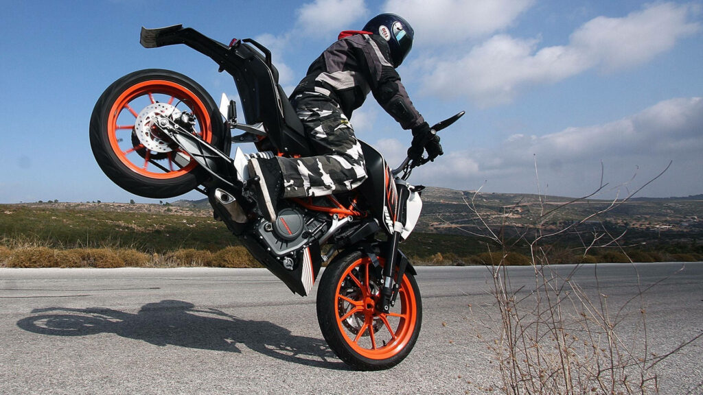 High-Octane KTM Duke 390 Wheelie Wallpaper in Scenic Open Road