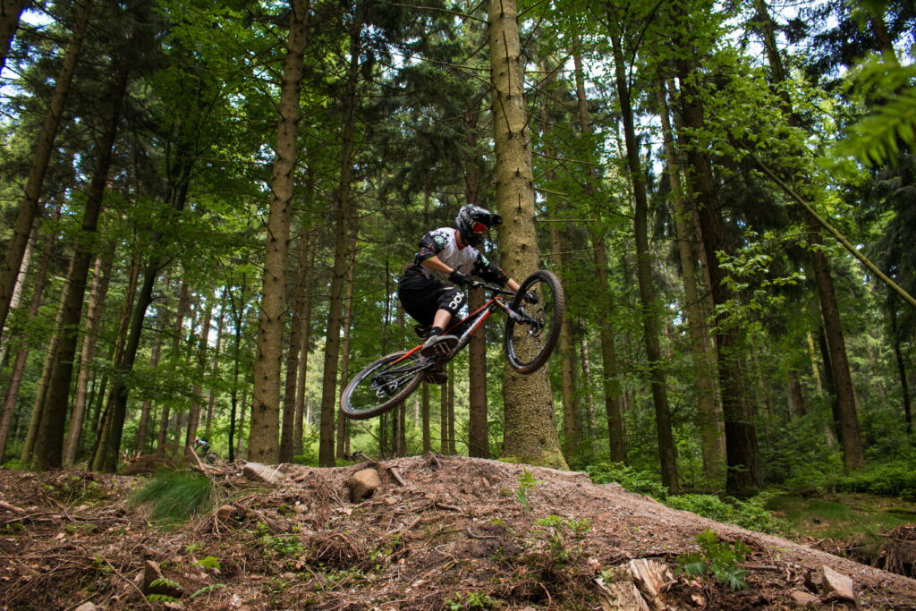 Thrilling MTB Moments: Cyclist Soars Through Forest in Breathtaking 4K Wallpaper