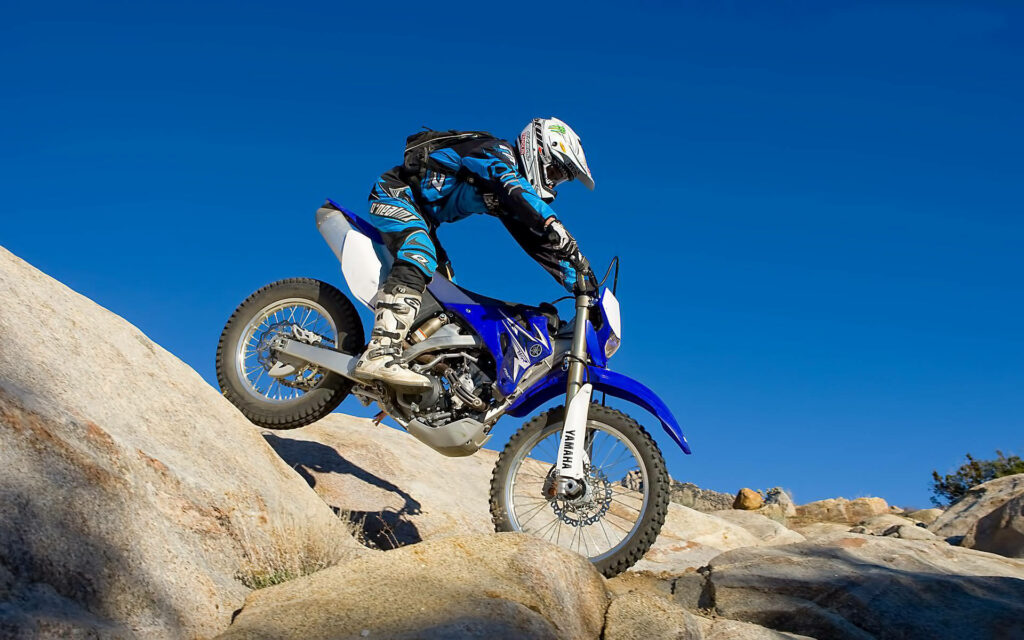 Thrilling Motocross Action on Rocky Terrain - Wallpaper Background