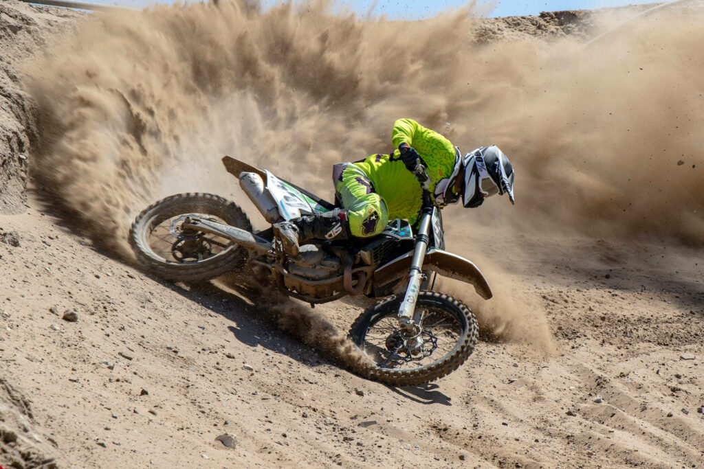 Thrilling Motocross Rider in Green Gear Kicks Up Dust - Wallpaper