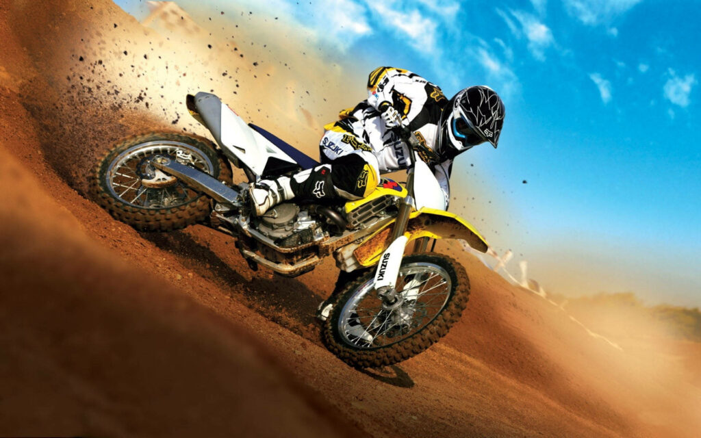 Thrilling Suzuki Dirt Bike Rider Drifting in Golden Desert Wallpaper
