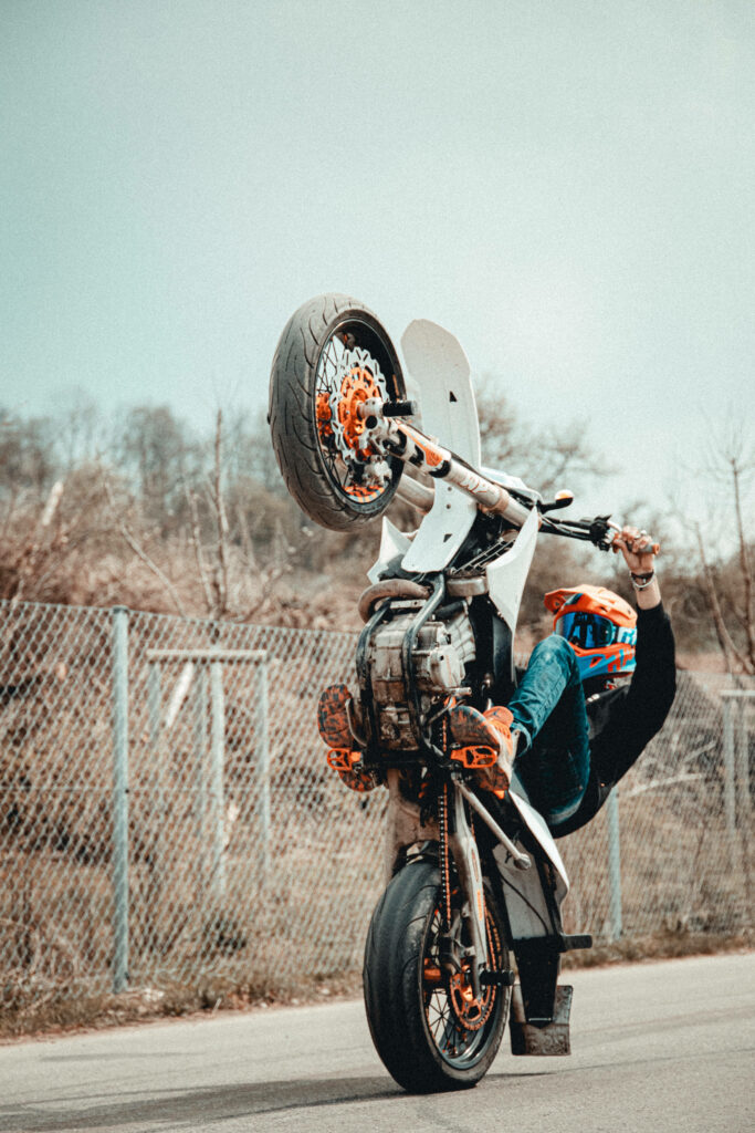 Thrilling Motorcycle Stunt Wallpaper: Daredevil Balancing on One Wheel