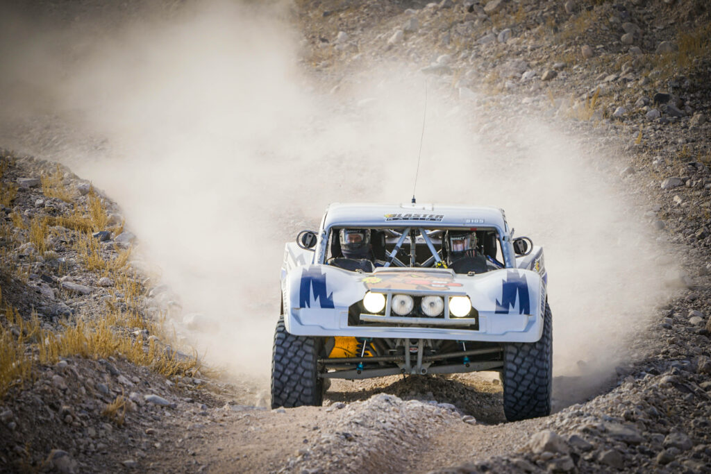 Rugged off-road rally vehicle speeding on mountain track Wallpaper