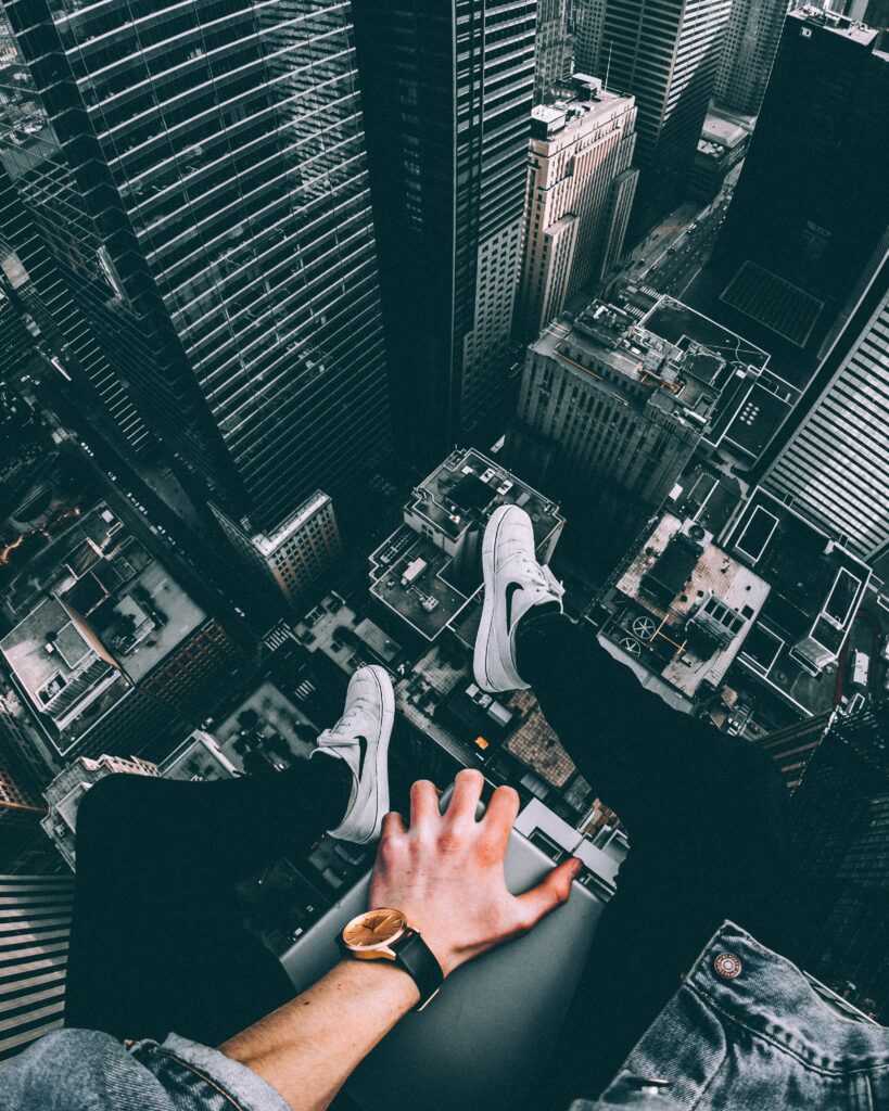 Thrilling Rooftop View: Individual Dangles Above City Skyline Wallpaper