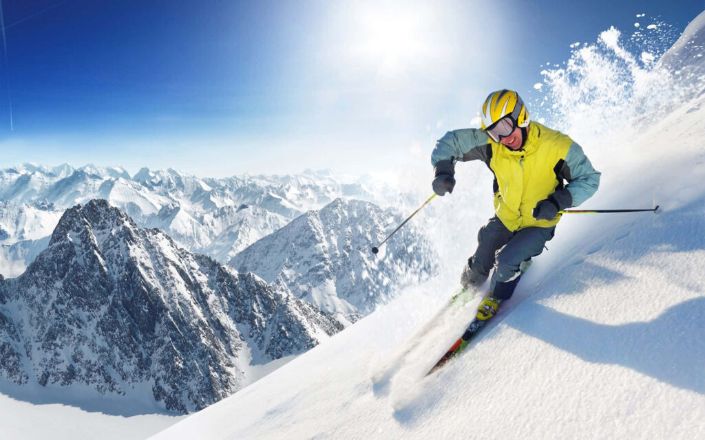 Thrilling Skier Wallpaper: Alpine Adventure Under Clear Blue Sky