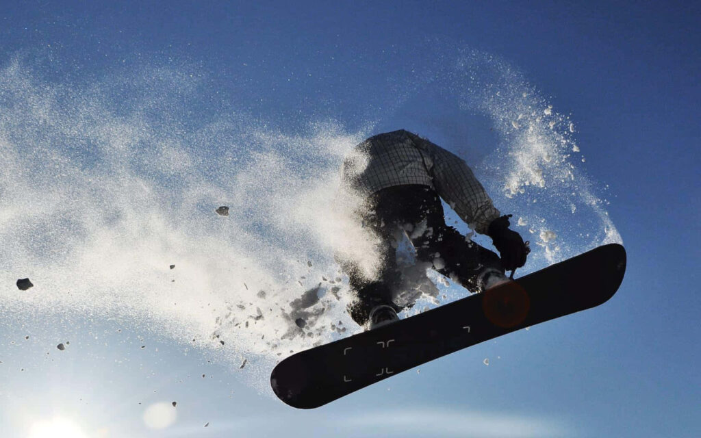 Snowboarder Jumps in Winter Sports Wallpaper Against Blue Sky