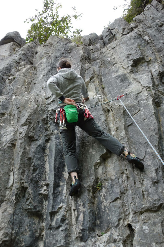 Adventurous climber skillfully ascending rugged mountainside showcasing sport climbing thrill Wallpaper