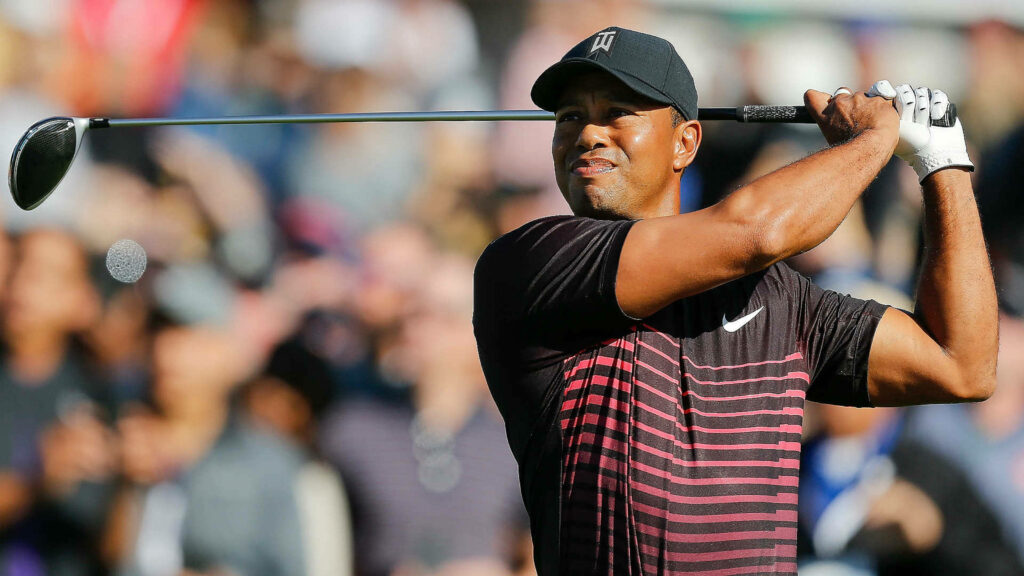 Tiger Woods focused driving golf ball 2018 Farmers Insurance Open black Nike outfit background crowd Wallpaper