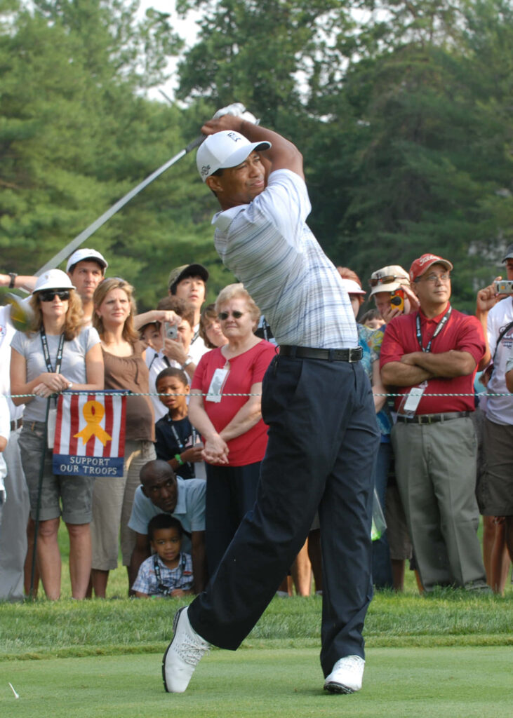 Tiger Woods mid-swing on golf course with focused crowd watching dynamic wallpaper background