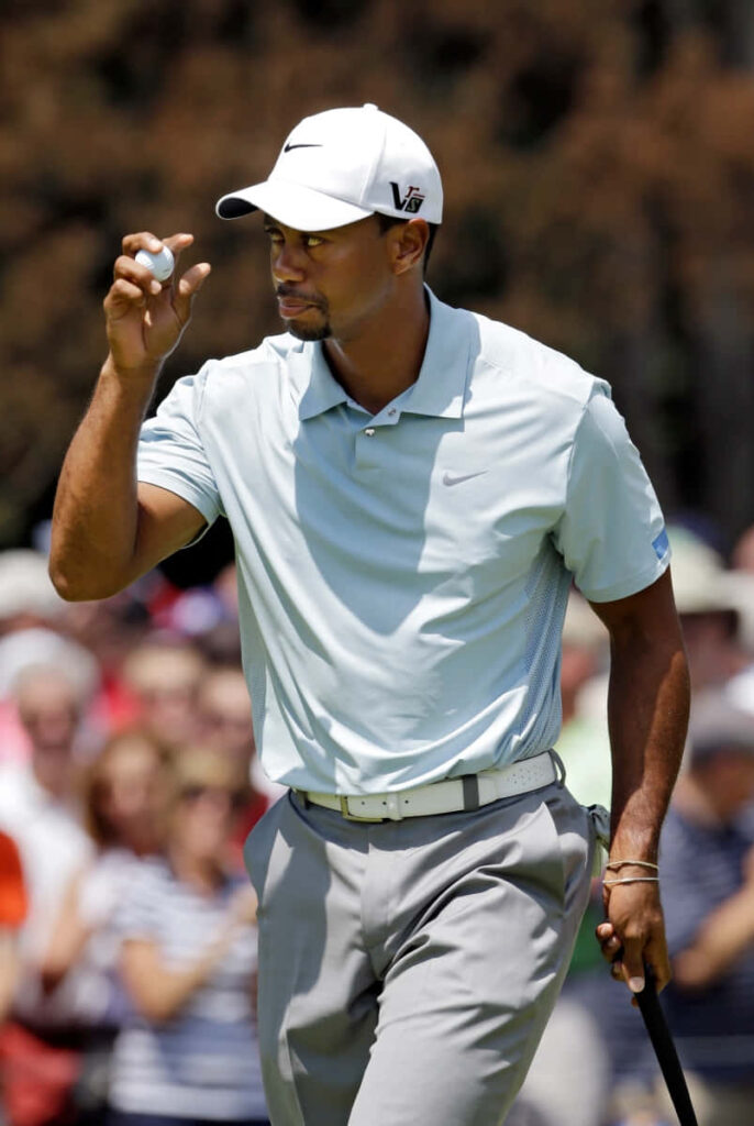 Tiger Woods confident on golf course holding ball with crowd background iPhone wallpaper
