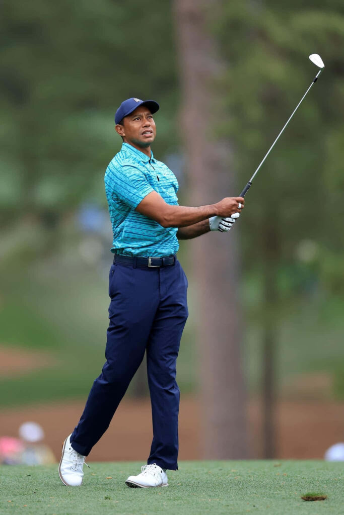 Tiger Woods mid-swing on lush golf course dynamic athletic iPhone wallpaper background