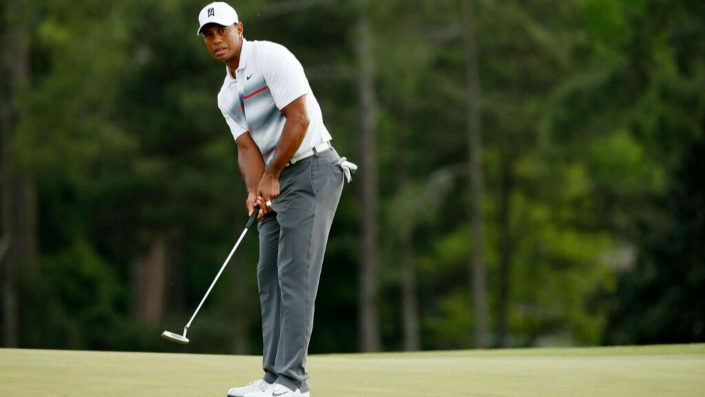 Tiger Woods mid swing on golf course focused poised with club lush green wallpaper background