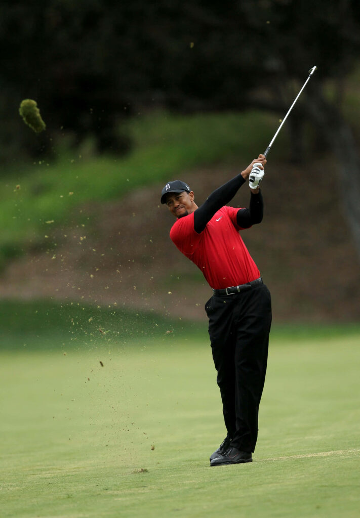 Tiger Woods mid-swing golf shot red shirt black pants dynamic golf wallpaper background