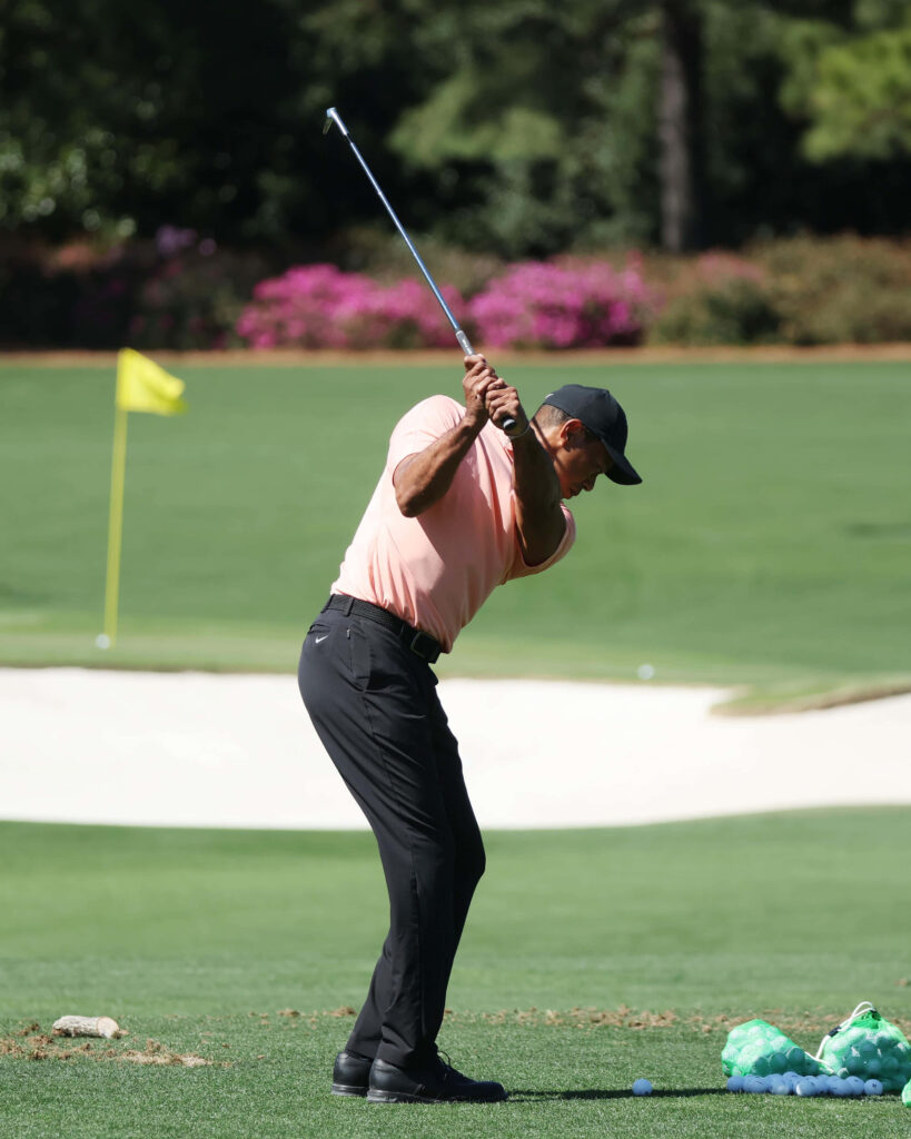 Tiger Woods mid-swing on green golf course focused athletic dynamic wallpaper background
