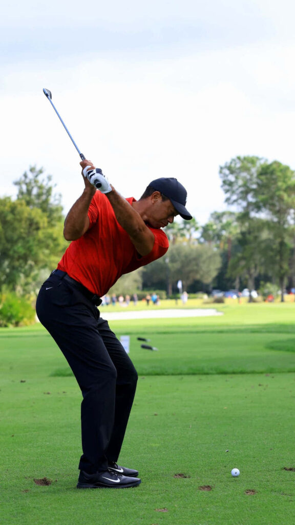 Tiger Woods powerful golf swing side view on lush green course vibrant iPhone wallpaper background