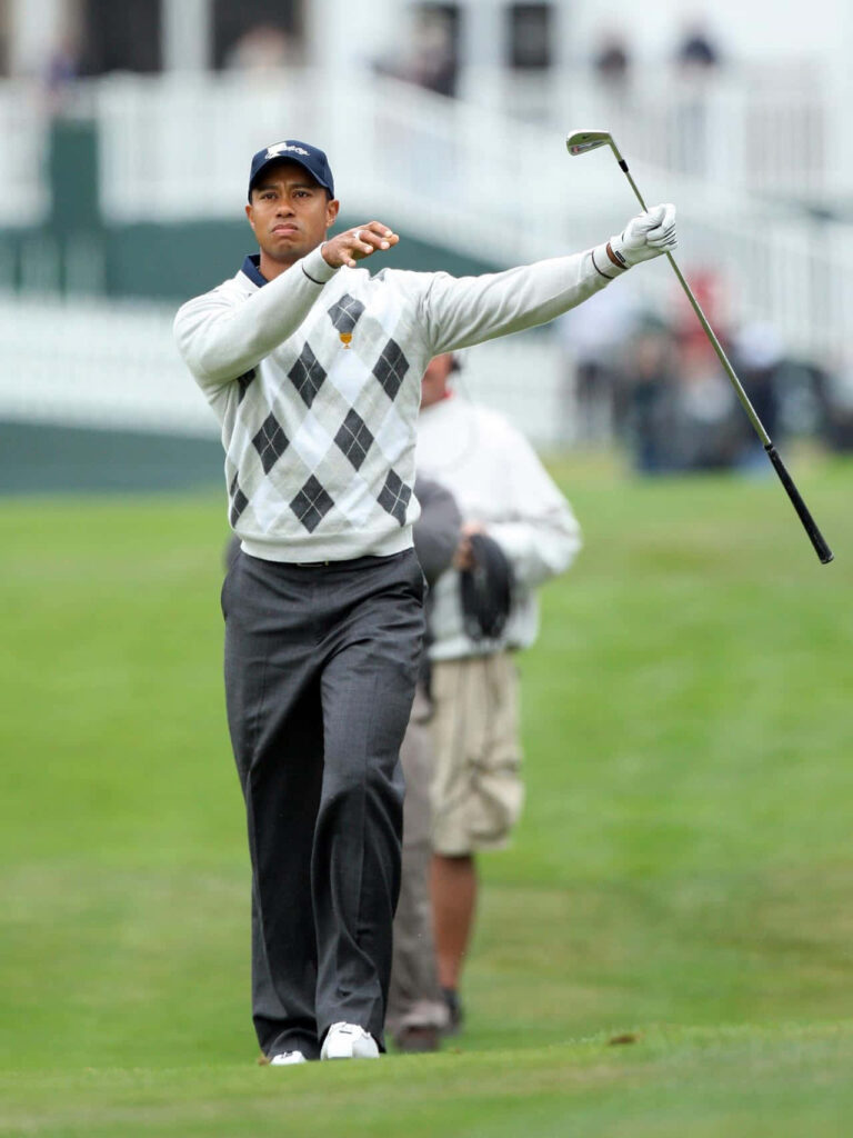 Tiger Woods in stylish sweater and cap ready to swing golf club on course iconic wallpaper