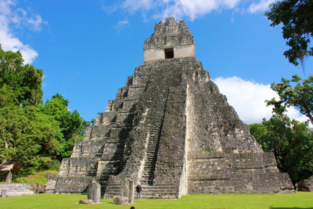 Tikal Temple I Mayan pyramid soaring above green Guatemalan jungle under bright blue sky Wallpaper