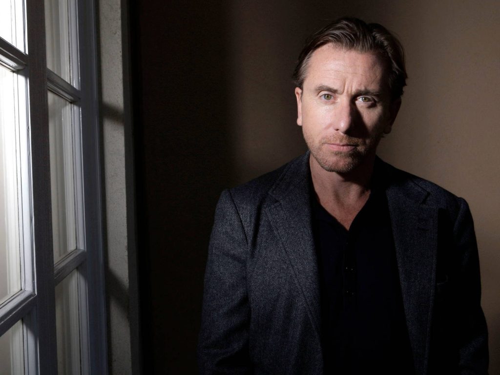 Tim Roth portrait in textured blazer with dramatic chiaroscuro lighting by window cinematic wallpaper