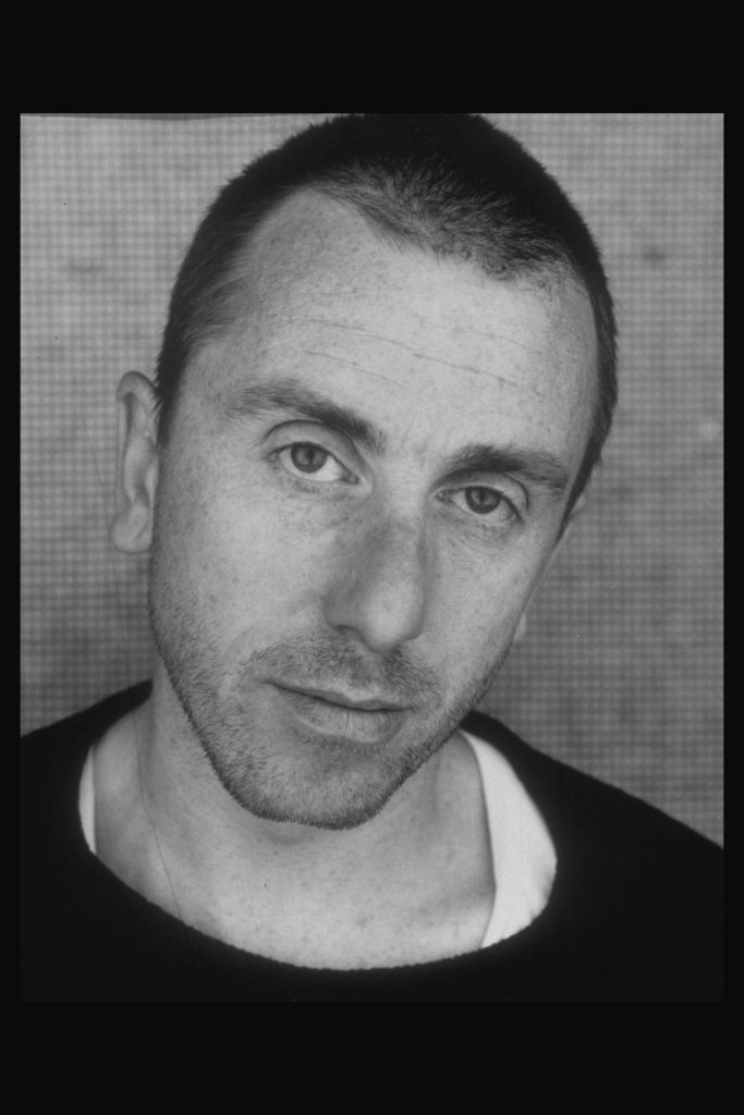 Close-up black and white portrait of young Tim Roth with buzz cut and intense gaze wallpaper