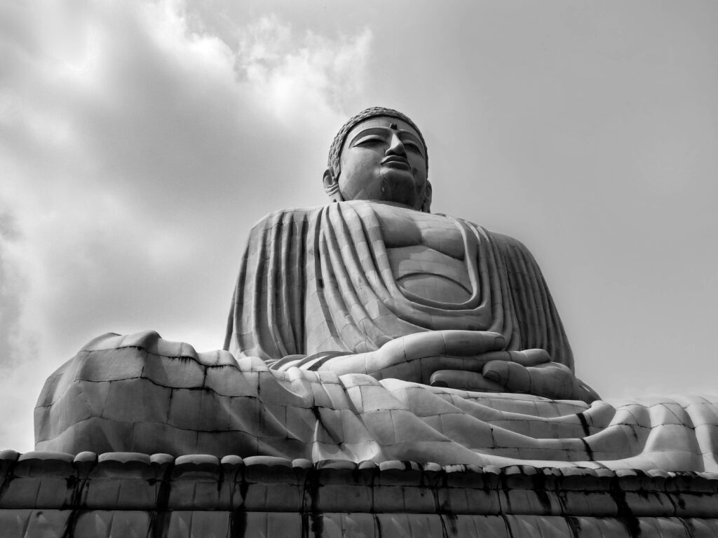 Majestic Monochrome: The Timeless Beauty of a Weathered Black Buddha Statue amidst an Enchanting Mossy Base Wallpaper