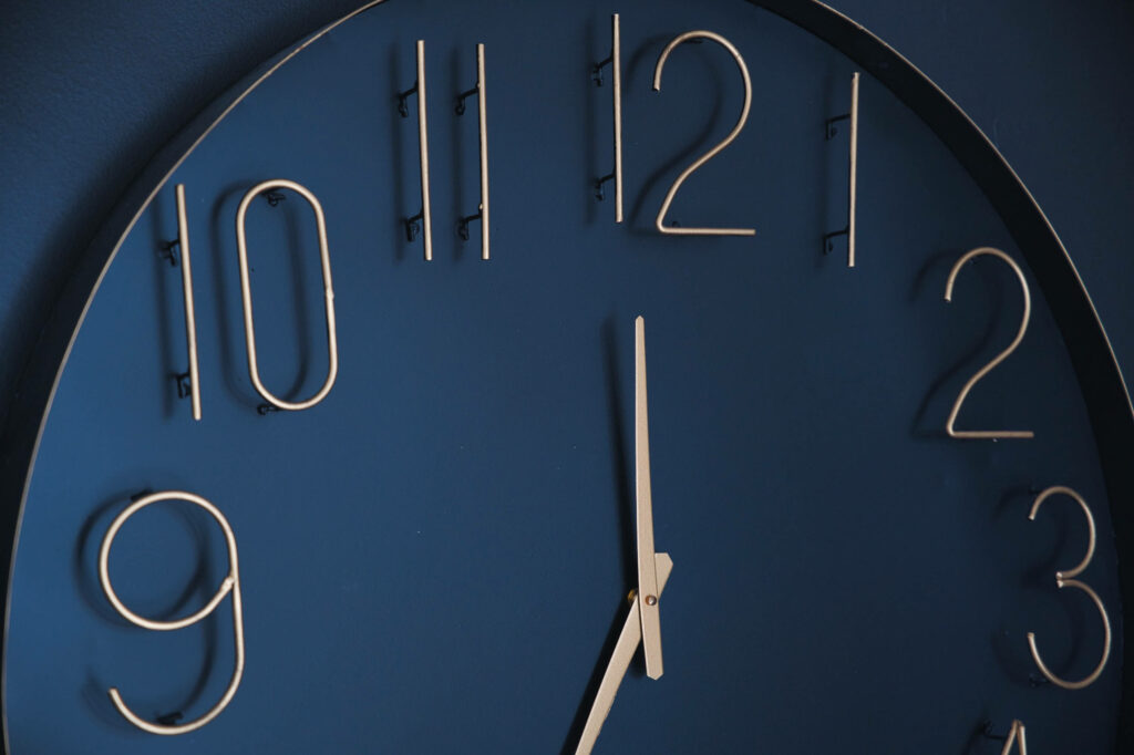 Indigo Elegance: A Contemporary Wall Clock Adorned with Metallic Engravings against a Minimalist Backdrop Wallpaper
