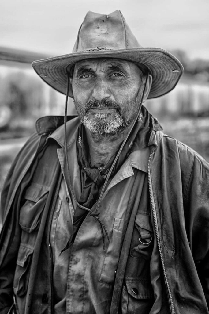 Greyscale portrait of old rugged cowboy with intense eyes wearing classic Western attire wallpaper