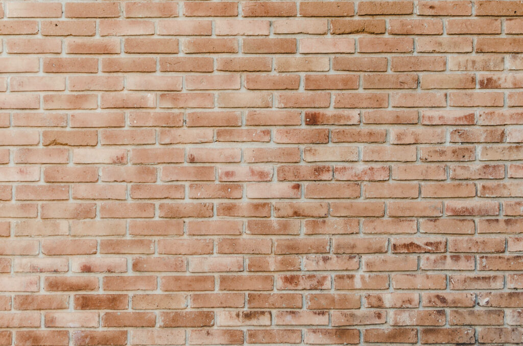 Rustic pale orange brick wall wallpaper with weathered texture and warm natural light backdrop