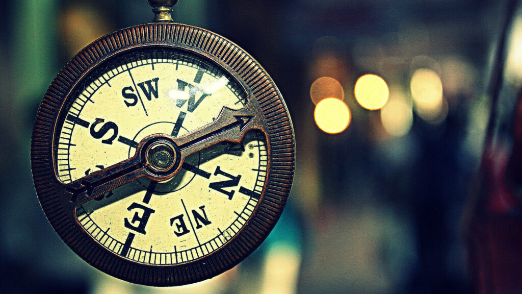 Antique brass nautical compass macro with warm dreamy bokeh background wallpaper design