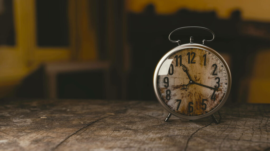 Timeless Treasure: Vintage Alarm Clock Sets the Tone on Wooden Table Wallpaper