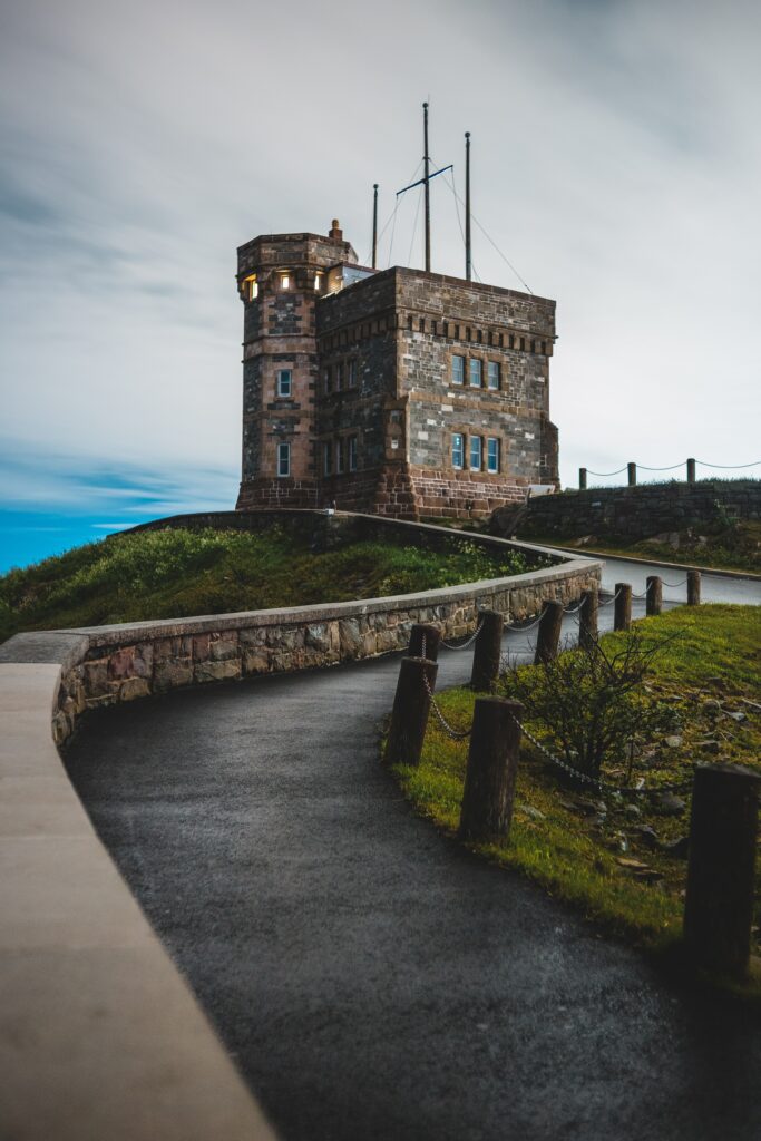 Historic stone castle at road end under dramatic dusk sky with earthy tones serene landscape wallpaper