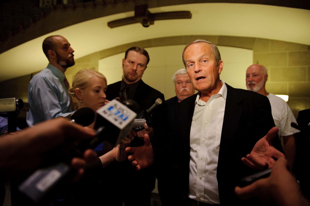 Todd Akin speaking at press conference surrounded by reporters and microphones indoors Wallpaper