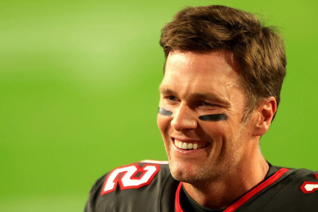 Tom Brady Smiling in Uniform: Iconic Football Wallpaper Background