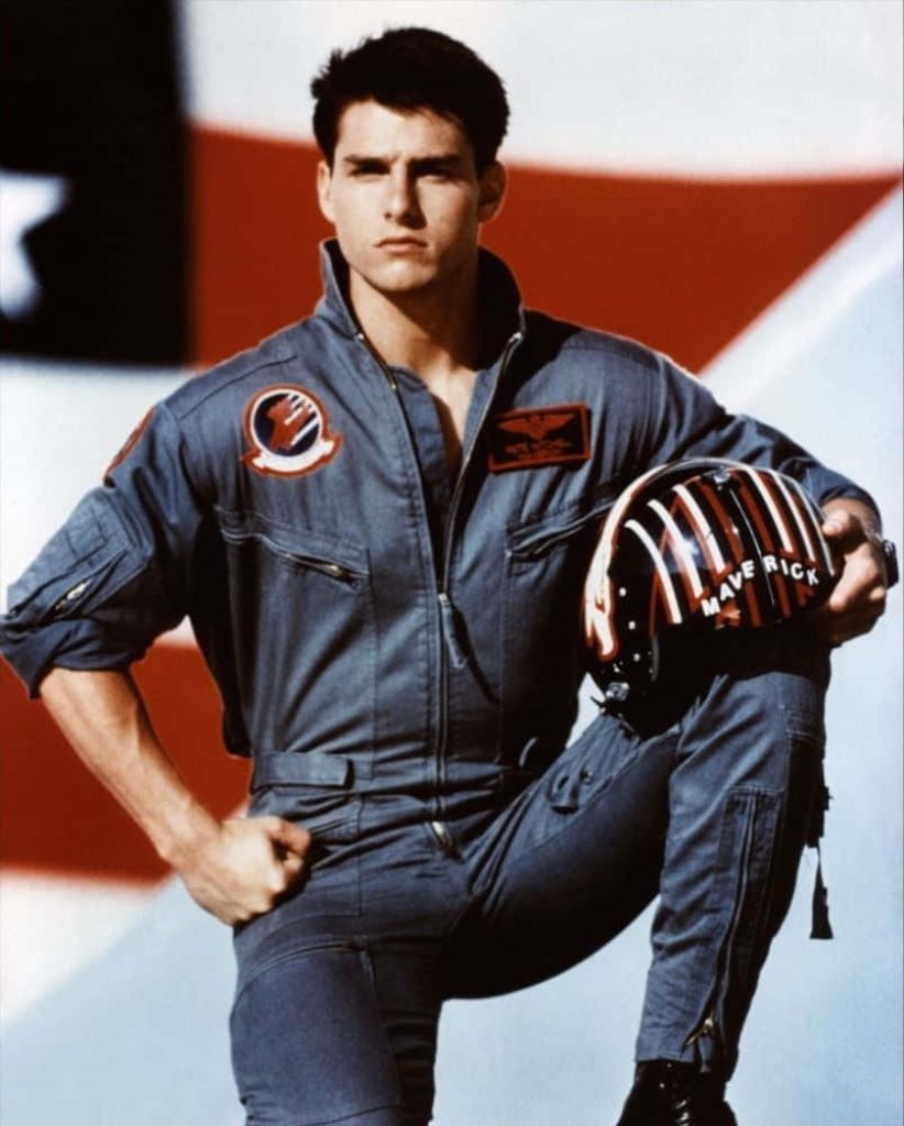 Tom Cruise as Maverick Top Gun in flight suit holding helmet with American flag background wallpaper