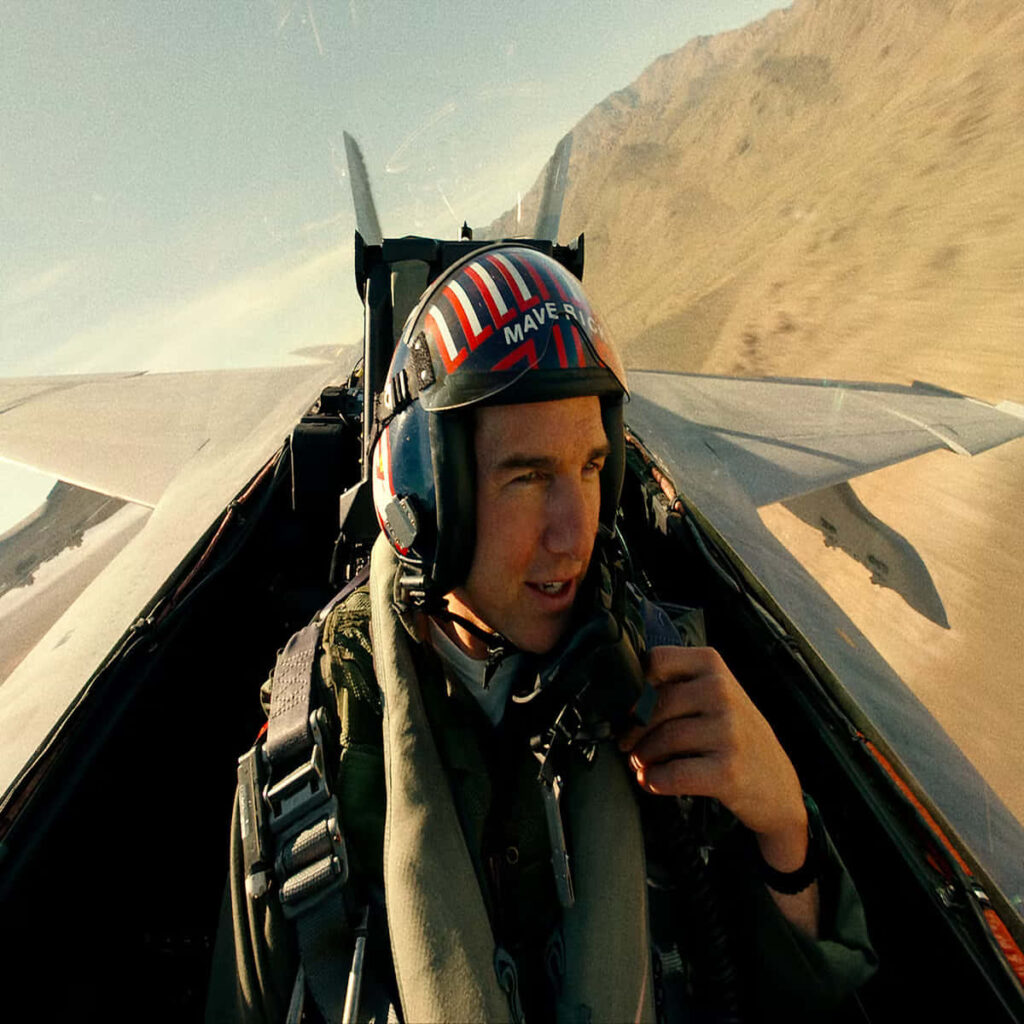 Tom Cruise as Maverick flying fighter jet over mountains Top Gun Maverick intense war game wallpaper