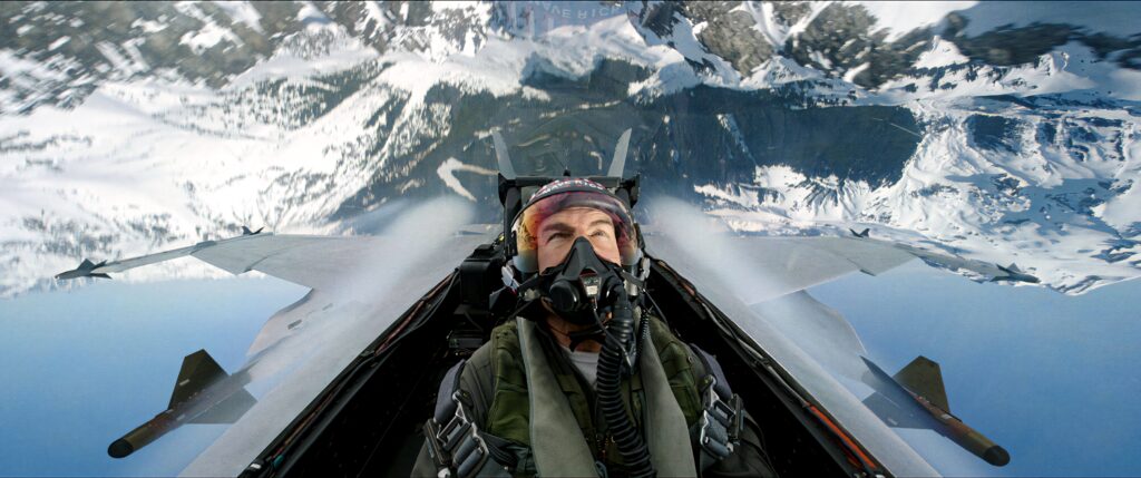 Tom Cruise as Pete Mitchell pilots fighter jet above snow-covered mountains Top Gun Maverick Wallpaper